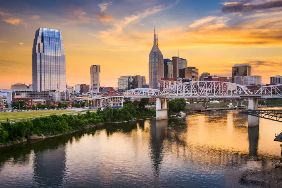Sunset view of downtown Nashville, Tennessee skyline from across a river.